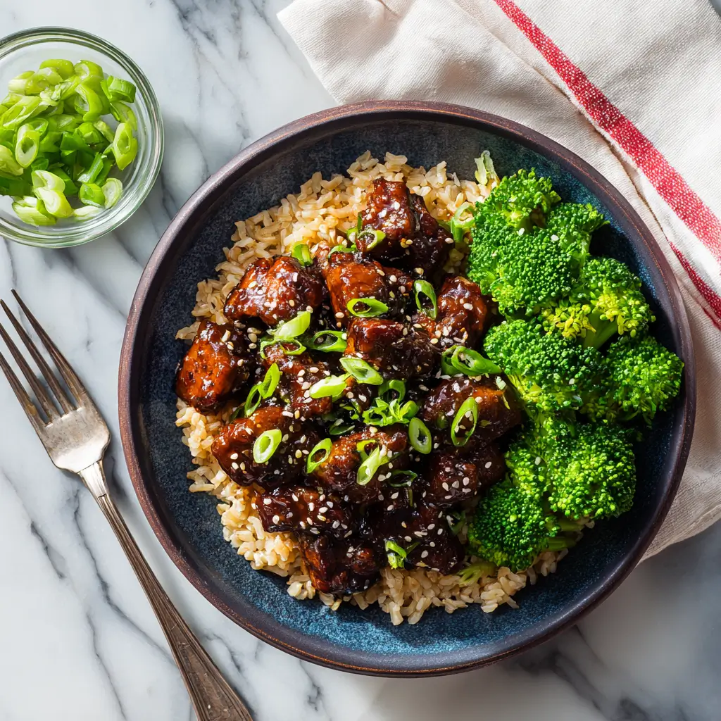 Tender slow cooker honey garlic chicken served over rice with sesame seeds and green onions.