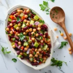 Overhead view of three bean salad with kidney beans, chickpeas, and green beans on white marble background